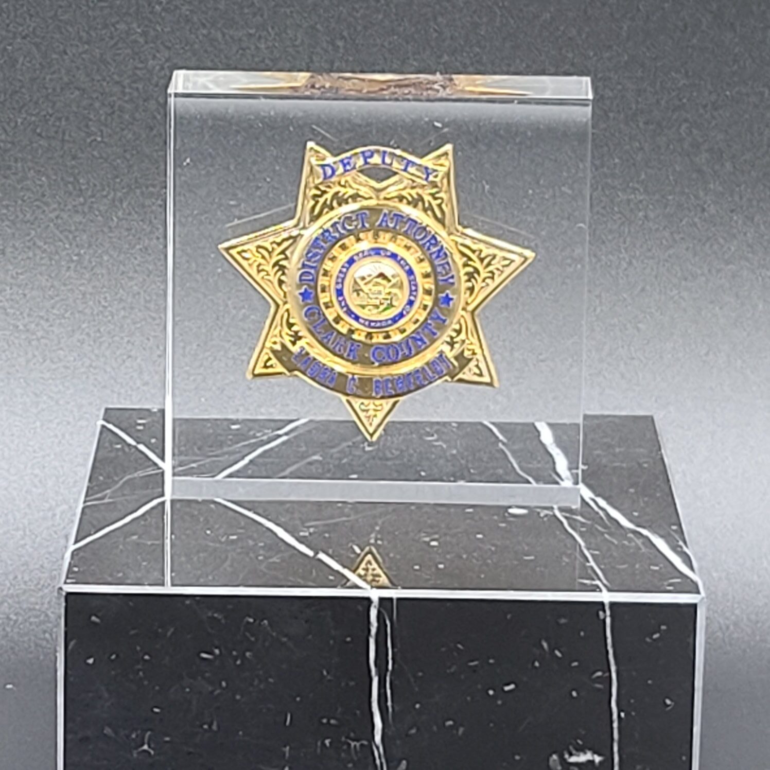 Clear acrylic award with embedded gold deputy district attorney badge on black marble base