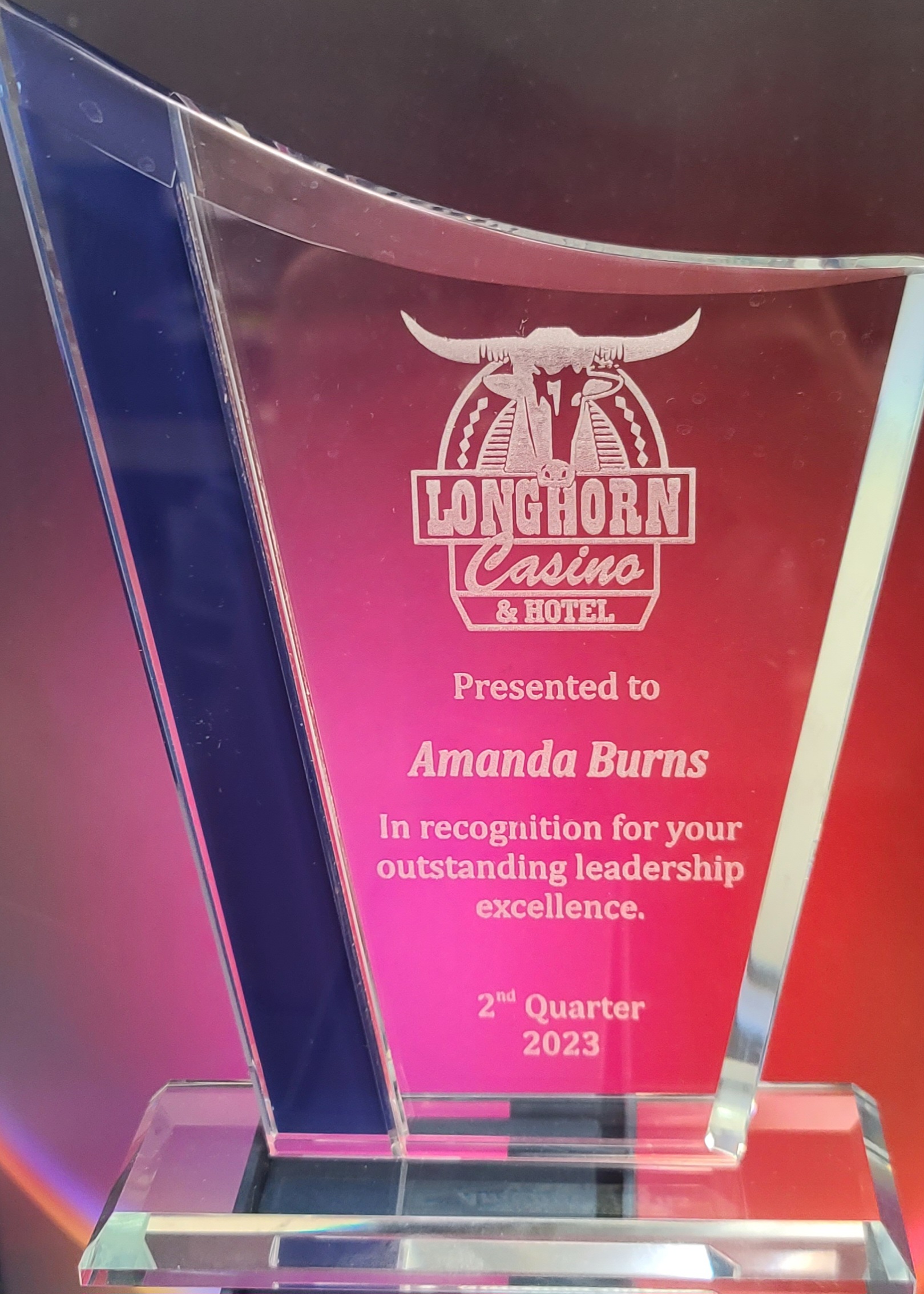 Clear crystal glass award with blue accent panel and laser-engraved casino logo for leadership recognition