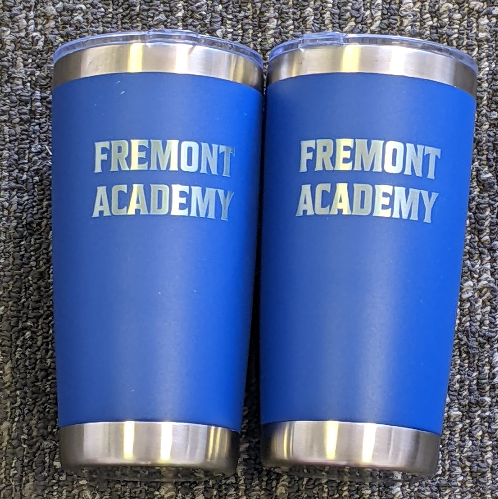 Two blue stainless steel tumblers with laser-engraved Fremont Academy text