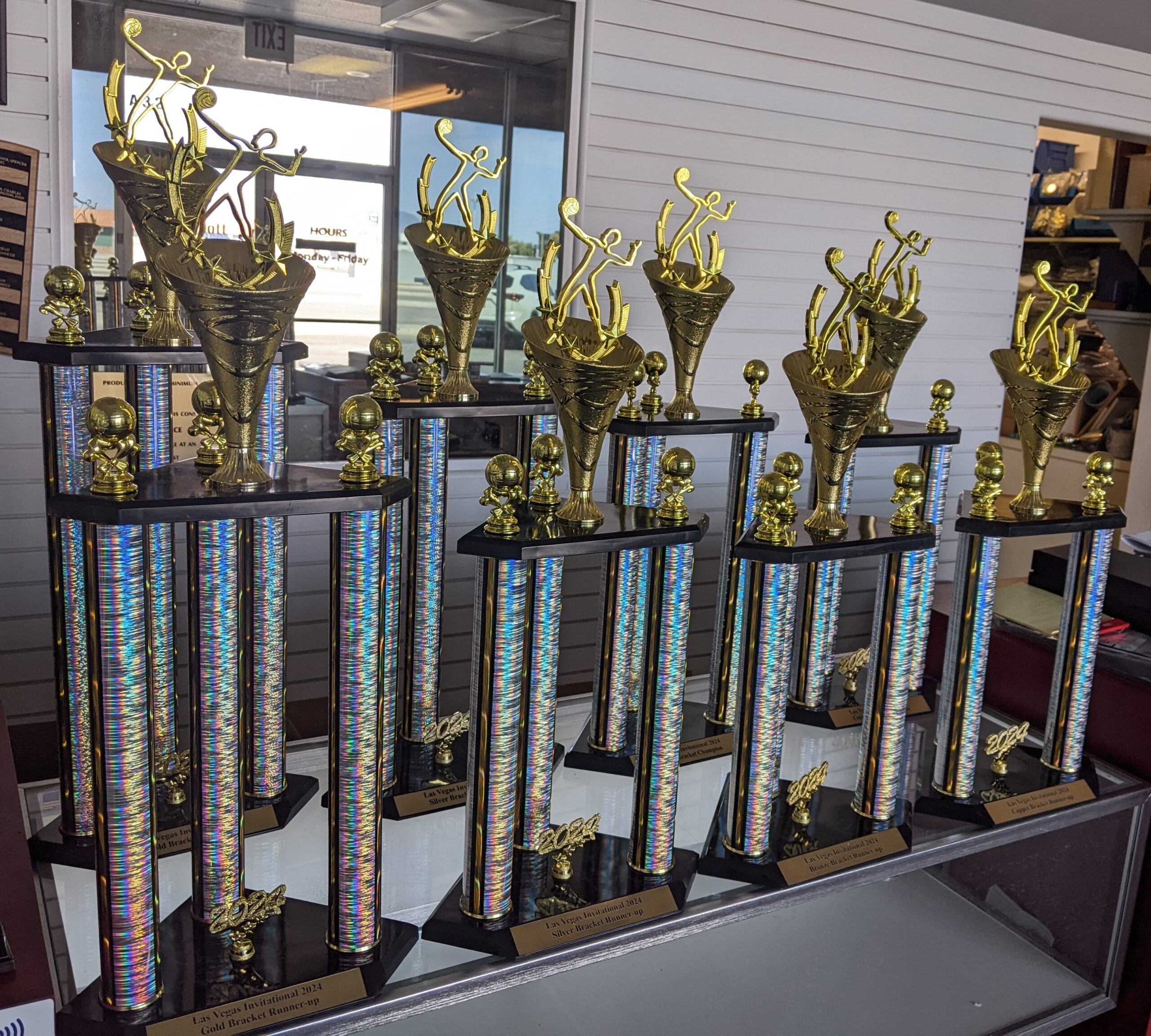 Multi-column holographic trophies with gold figure toppers displayed in a trophy shop