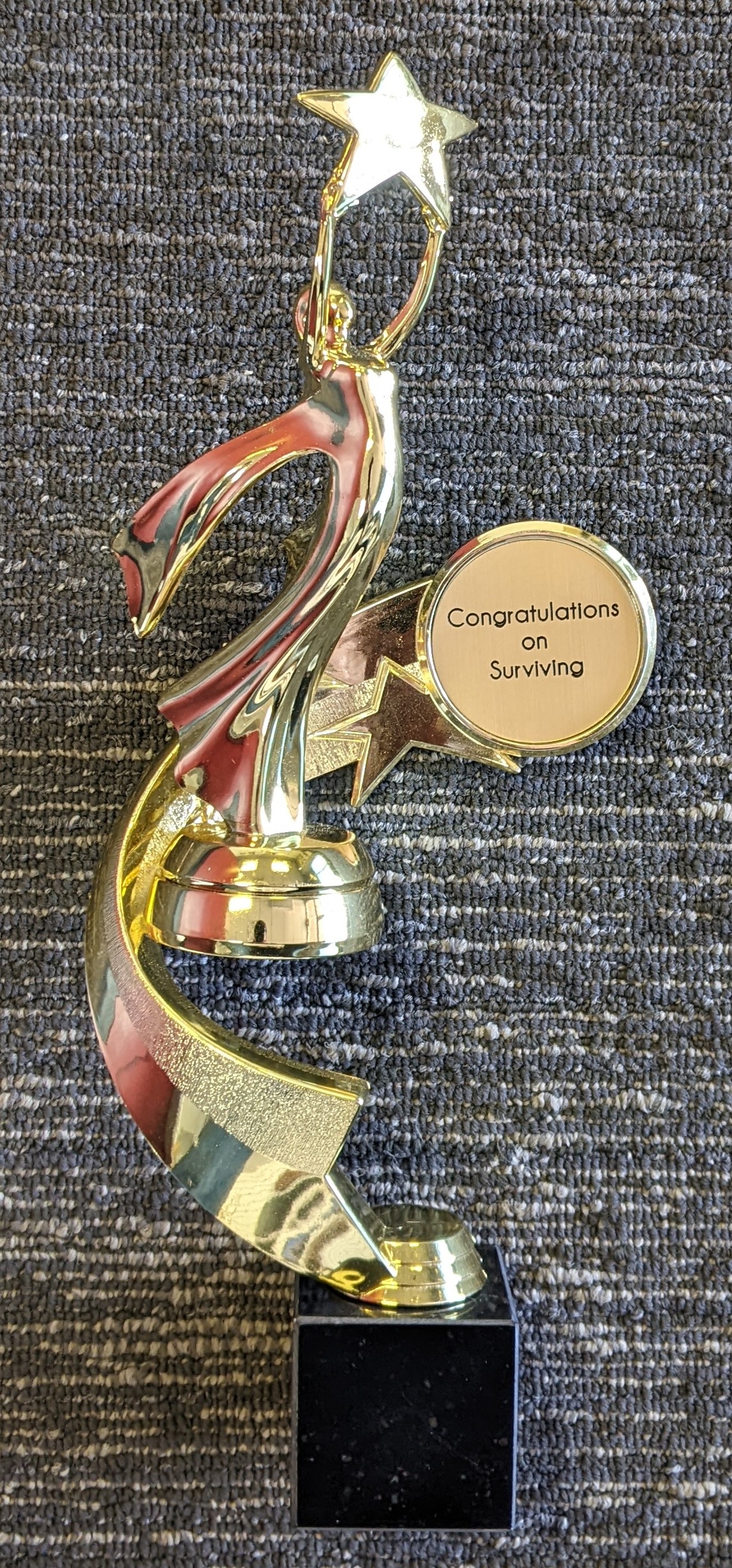 Gold and red victory figure trophy with star topper and engraved congratulations medallion on black marble base