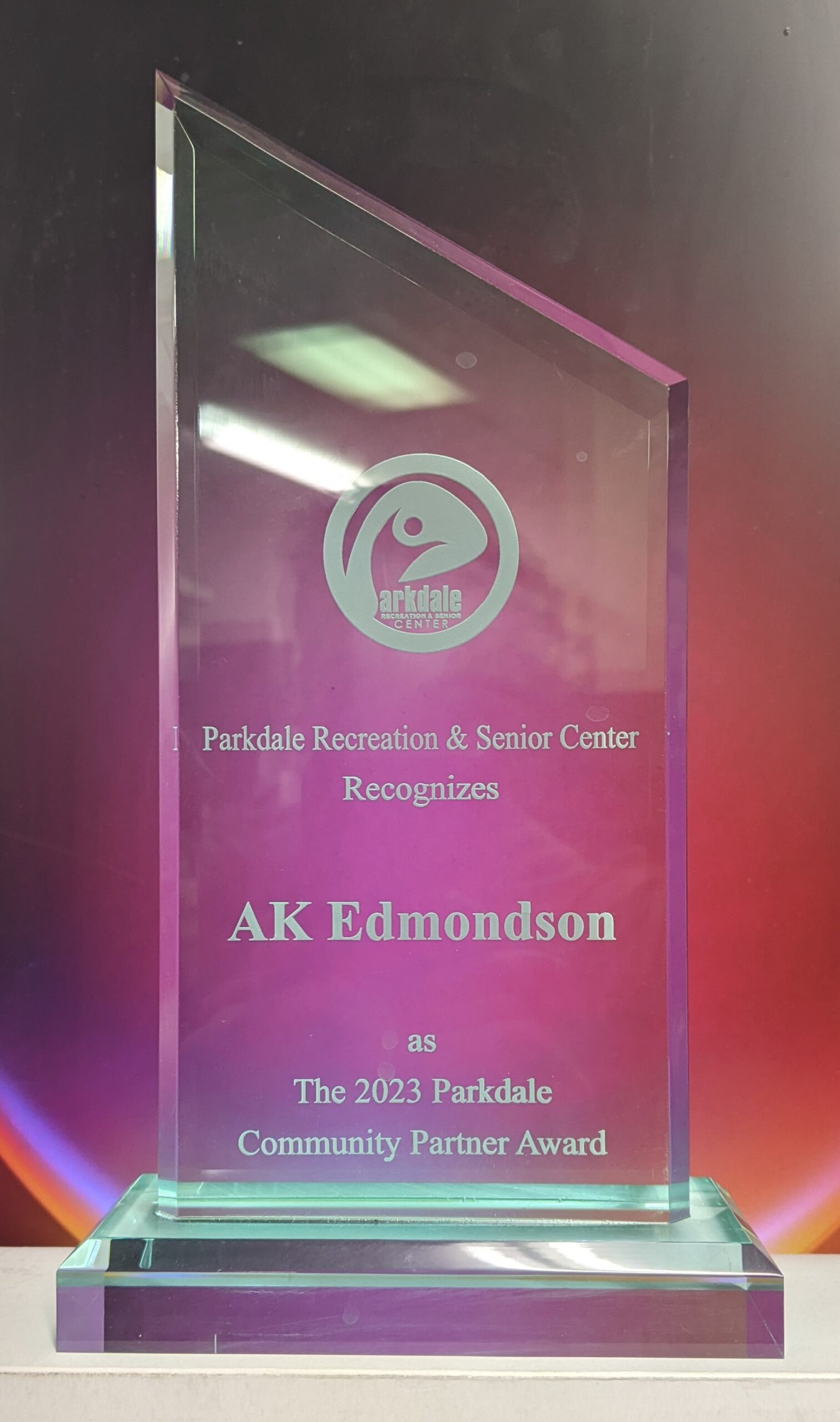 Clear glass peak award with laser-engraved logo and community partner recognition on beveled glass base