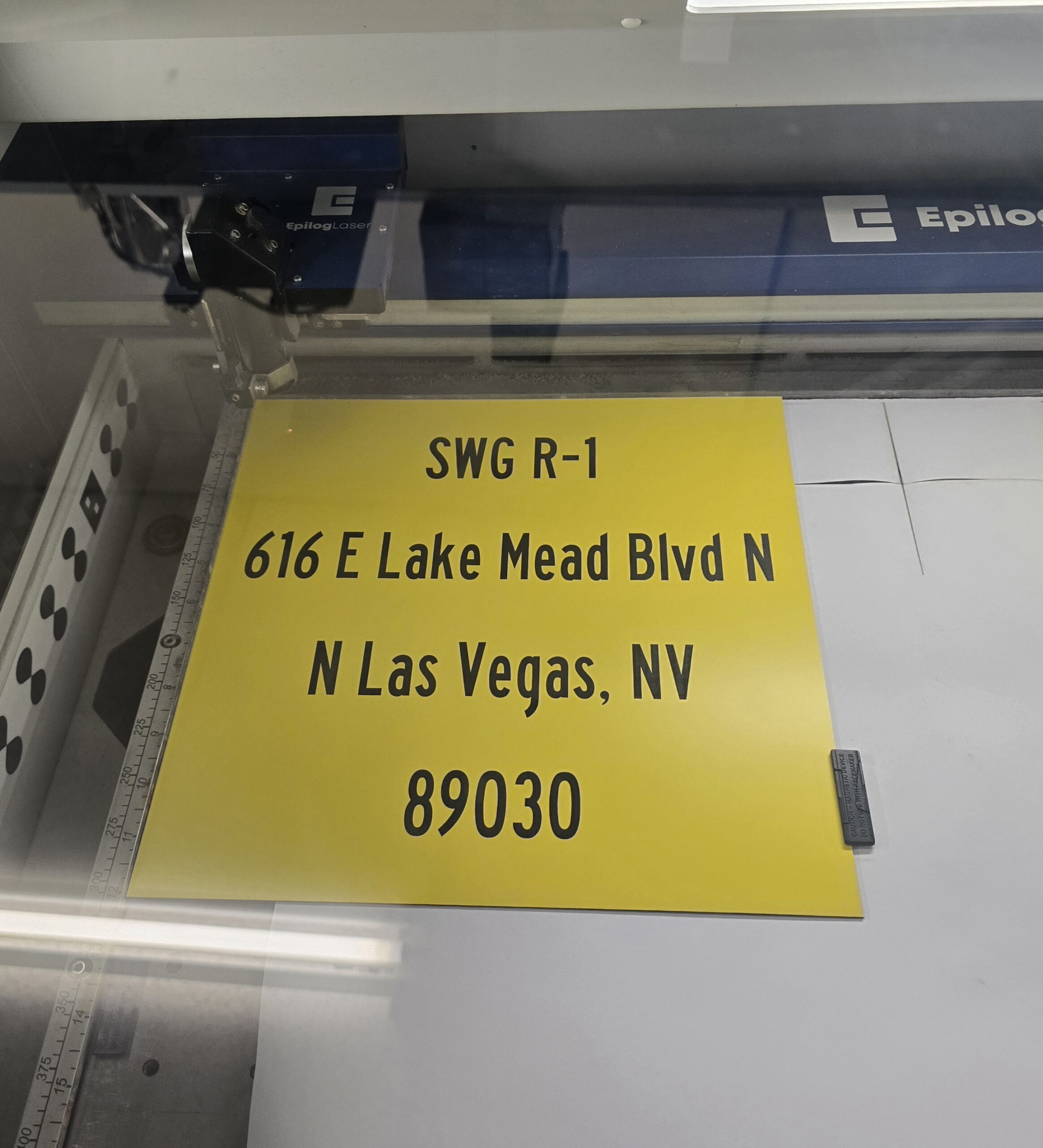 Custom yellow laser-engraved address sign being cut on Epilog laser machine, North Las Vegas Nevada signage