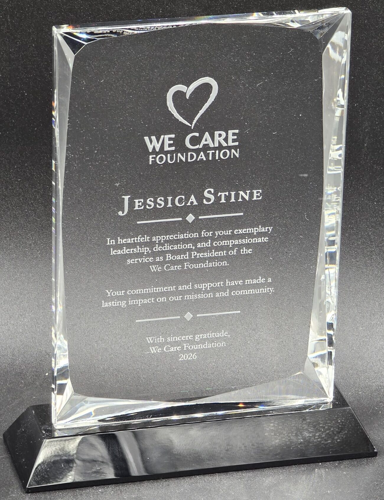 Clear beveled crystal rectangle award on black base, laser-engraved for We Care Foundation board president recognition, Las Vegas